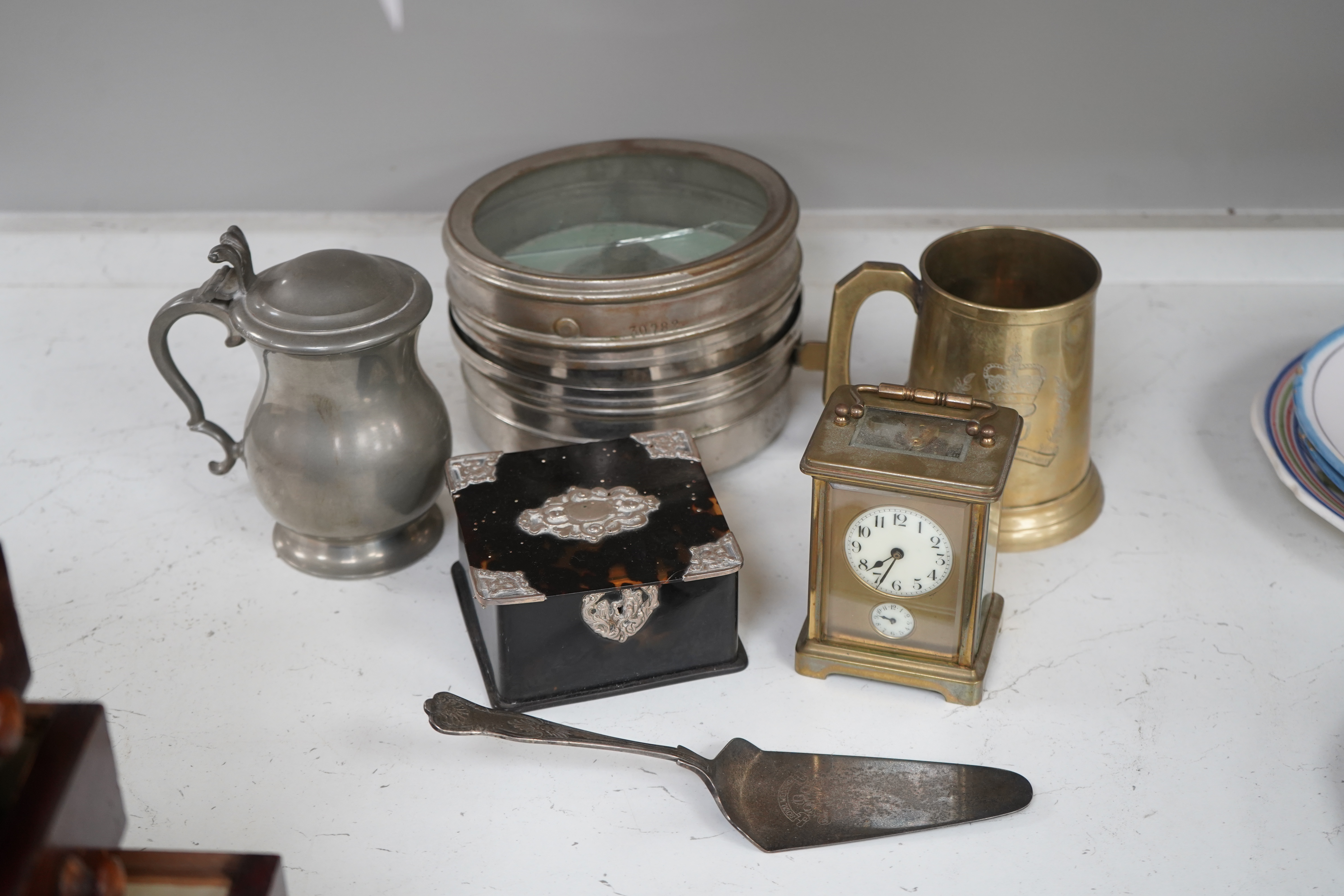 A small collection of metalware to include a white metal mounted tortoiseshell box, brass cased carriage clock with subsidiary dial and a pewter tankard. Condition - poor to fair